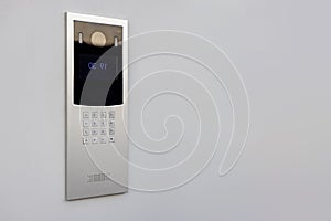 Doorbell with video camera and microphone, on the white wall of an apartment building, doorbell camera