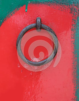 doorknocker circle on red painted wooden door