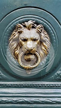 Doorknocker with head of lion on a green wooden door