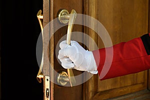 The doorman opens the hotel door hands in white gloves