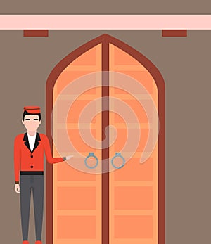 Doorman standing in front of hotel entrance doors. Young man in uniform working as belboy