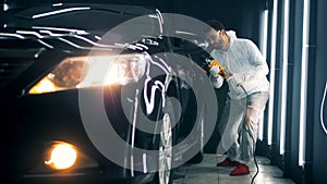 Doors of a black car are getting buffed by a male technician