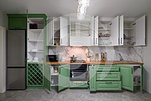 Doors open and drawers pulled out at new green and white kitchen furniture