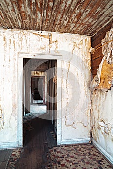 Doorway in an old abandoned home in Bannack ghost town, Montana. Peeling wallpaper and drywall photo