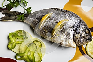 Dorada fish cooked in the oven with lemon, pimento and green onion served on a tray on a wooden table