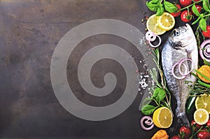 Dorada, fresh fish with vegetable, lemon, herbs, onion, paprika, cherry tomatoes, onion, salton dark vintage background.