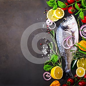 Dorada, fresh fish with vegetable, lemon, herbs, onion, paprika, cherry tomatoes, onion, salton dark vintage background. Copy spac