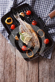 Dorado fish cooking on the grill pan close-up. vertical top view