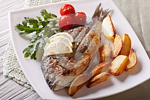 Dorado fish with fried potatoes and lemon closeup. horizontal