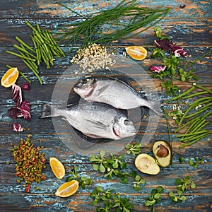 Dorado and natural ingredients for healthy food on rough dyed wooden background.