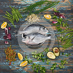 Dorado and natural ingredients for healthy food on rough dyed wooden background.