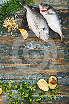 Dorado and natural raw ingredients for healthy food on rough dyed wooden background.