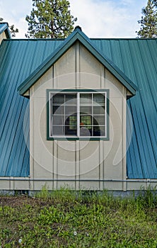 A dormer on the first floor of a cottage with a standing seam metal roof