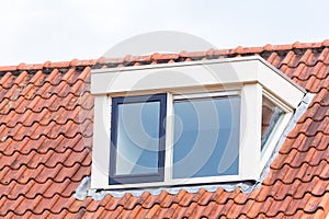 Dormer window on roof of attic with roof tiles