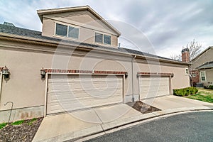 Dormers with gable rood above garage of house with wide white garge doors