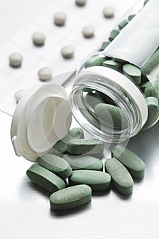 Dose of medicines - green pills pouring out of a glass bottle