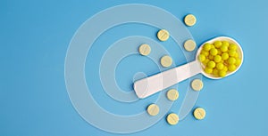 A dosed spoon filled with yellow vitamin C on the background of tablets. Free space for text photo