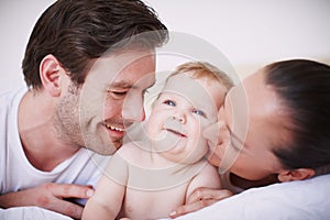 Doting on their little one. Two loving young parents spending time with their adorable baby girl indoors.