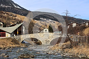 The double arch stone bridge over the river Julia in the Swiss alps village Savognin