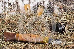 Double-barrel weapon with cartridges and hunting knife, on the background of birch and dry grass