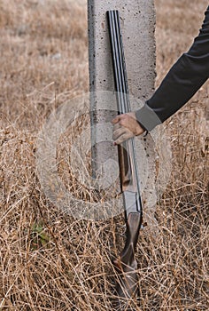 double-barreled shotgun with cartridges, leaning against a pole. Hunting concept ,