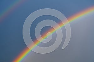 Double, beautiful, multi-colored rainbow on blue sky after summer downpour