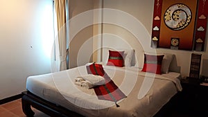 Double bed along White Bedding and White Red Pillow with modern art warm tone picture wall on the background