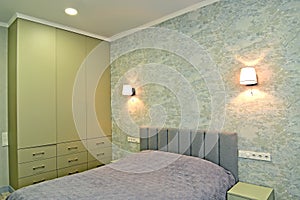 Double bed and wardrobe in the bedroom with wall lamps