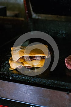 Double beef burgers with cheese on a plancha grill. Food preparing concept photo