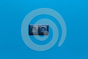 Double black socket power home energy supply electricity on blue wall background