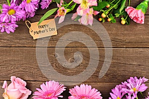 Double border of flowers with Mothers Day gift and tag against rustic wood