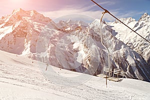 Double-chair ski lift on the background of the Caucasus Mountains ridge on a sunny winter day