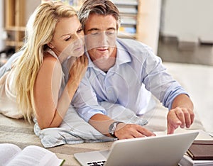 Double checking their plans online. a mature couple lying on their living room floor doing some online research.