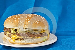 Double cheeseburger on blue linen background