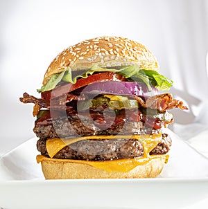 Double cheeseburger layered with toppings on white background.