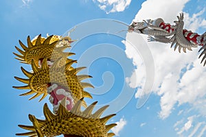 double Chinese dragon statue color gold and silver with beautiful pattern of scale around the red pole isolated on blue sky