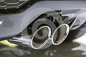 Double chrome exhaust pipe of powerful sport car with grey plastic details
