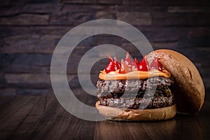 Double craft beef burger with cheddar cheese, caramelized onion.and pepper pout on wood table and rustic background