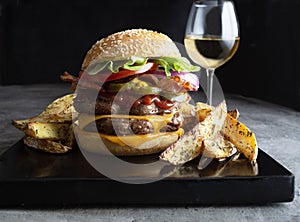 Double decker cheeseburger with potato wedges and a glass of whitewine