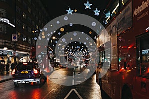 Double Decker red buses, black cabs and cars on Oxford Street, London, decorated with Christmas Lights.