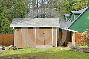 Double door wooden shed with gray gable roof on a sunny day in Washington State