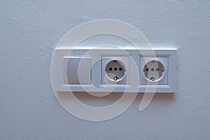 Double electrical wall socket with light switch on white wall