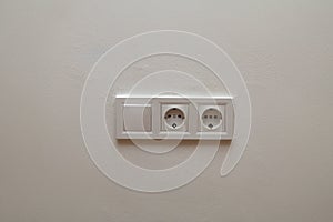 Double electrical wall socket with light switch on white wall