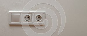 Double electrical wall socket with light switch on white wall