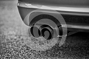 Double exhaust pipes of a modern sports car, black and white