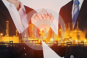 double exposure of arm wrestling between businessman and businesswoman with oil refinery plant background