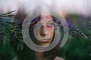 Double exposure of a beautiful girl with a purple lupine flower. Art photo. Soft focus. Close-up portrait. Beautiful eyes