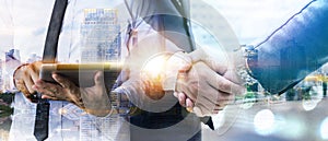 Double exposure of business handshake for successful of investment deal and business man using digital tablet