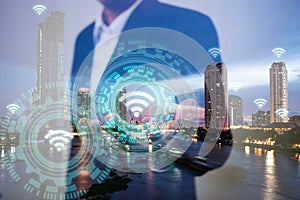 Double exposure of business, technology and internet connection concept. Businessman using icon wifi on hand and modern city