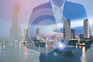 Double exposure businessman hand holding and touch screen smart phone with modern city background.
